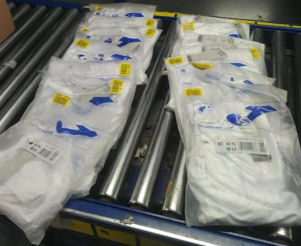 Kontrola vrácených balíků s drahým oblečením na pásu v logistickém depu
